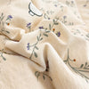 A beige fabric with a light floral pattern and a small white cartoon animal design, folded and draped.