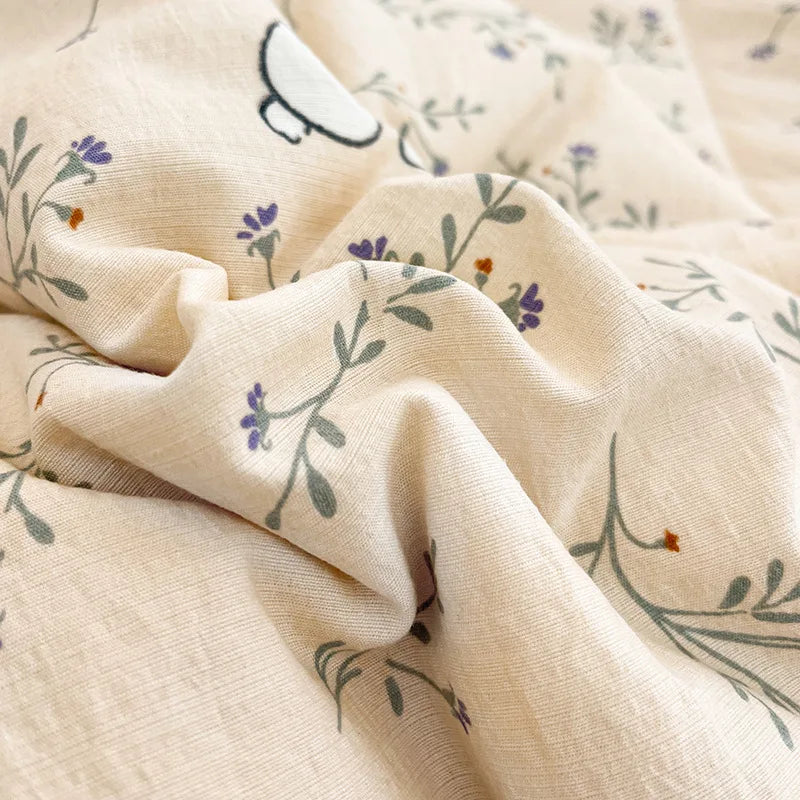 A beige fabric with a light floral pattern and a small white cartoon animal design, folded and draped.