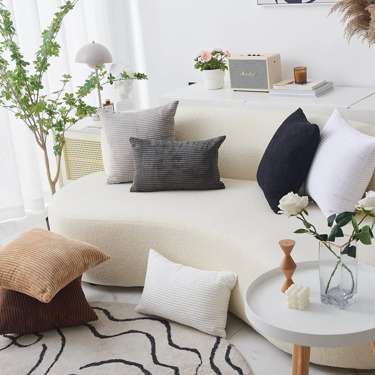 A collection of neutral-toned throw pillows, including gray and white textured covers, displayed on a light sofa.