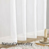 A close-up of sheer white voile curtains hanging vertically against a white wall.