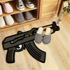 A black gun-shaped rug with white and black striped shoes is placed on a light wooden floor.