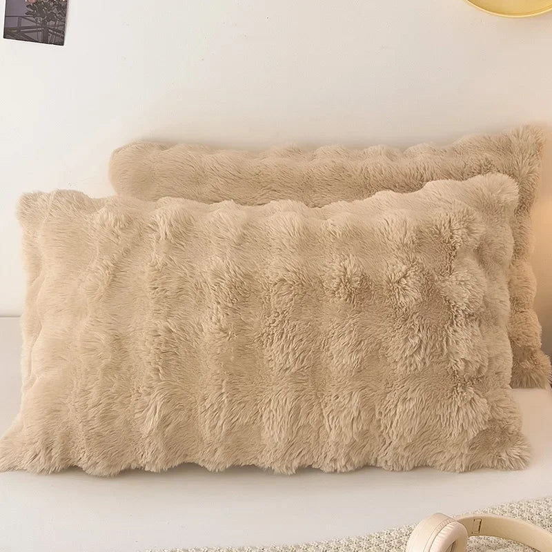 A beige faux fur decorative pillow cover lying on a white surface.
