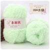 Two balls of light green soft coral velvet yarn for crafting displayed next to a wooden stick.