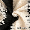 Close-up of a soft fabric with black and white speckled pattern, showing texture and folds.