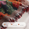 A close-up of a romantic floral jacquard sofa throw blanket with fringed edges in rich autumnal colors.