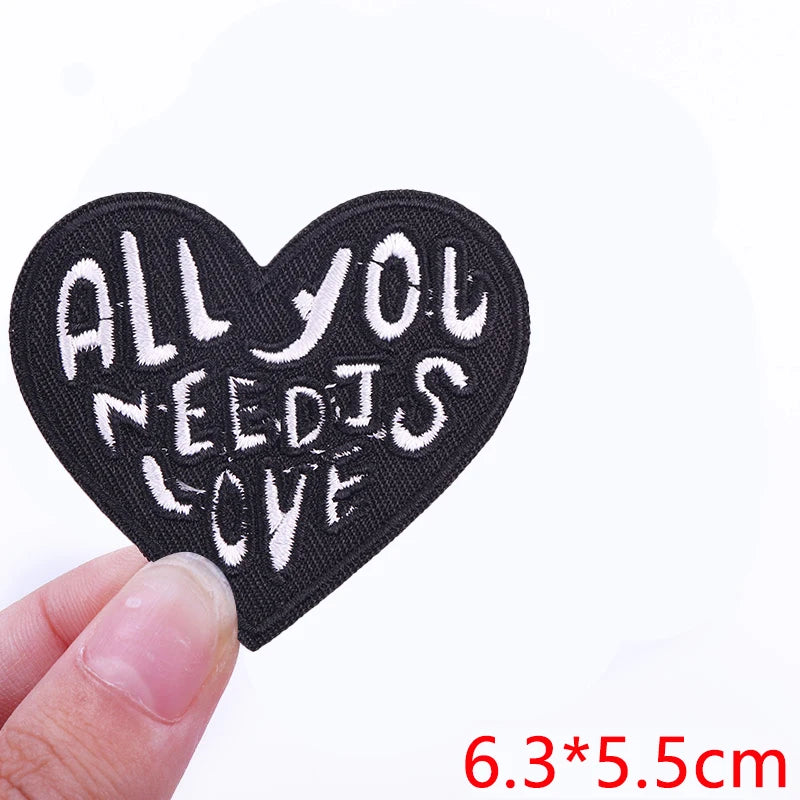 Black heart shaped embroidered patch with the text All you need is love