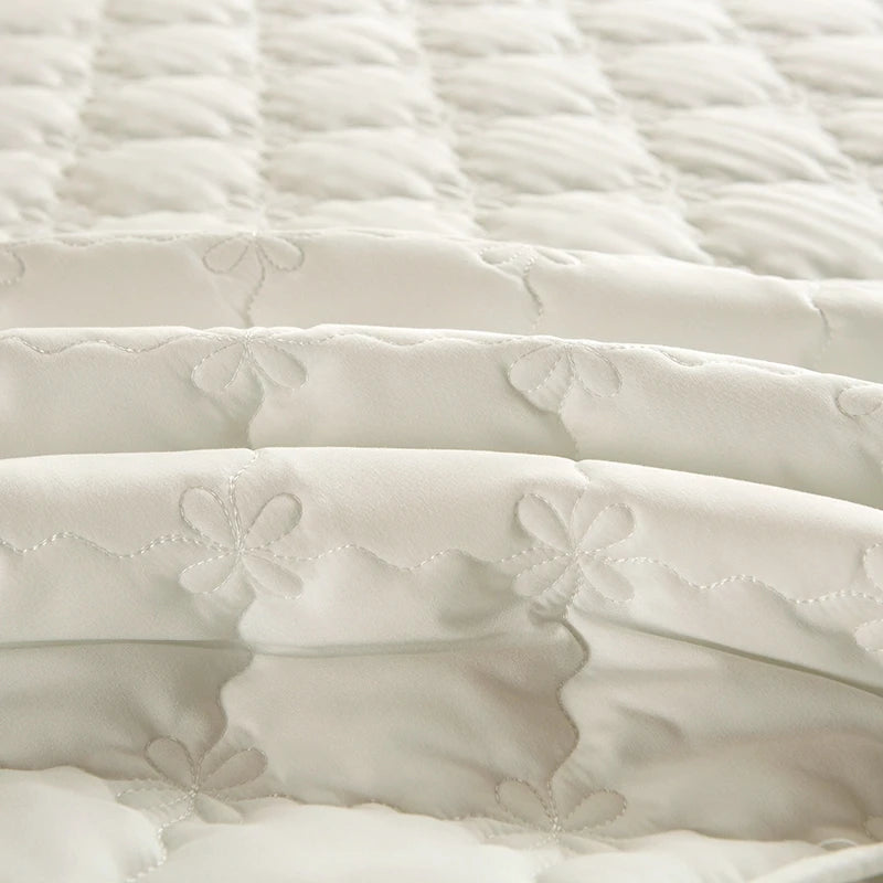 A close-up of a white thickened quilted bed skirt cover showing soft folds and stitching.