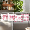 Decorative pillow covers featuring a pink bow pattern on white fabric displayed on a sofa.