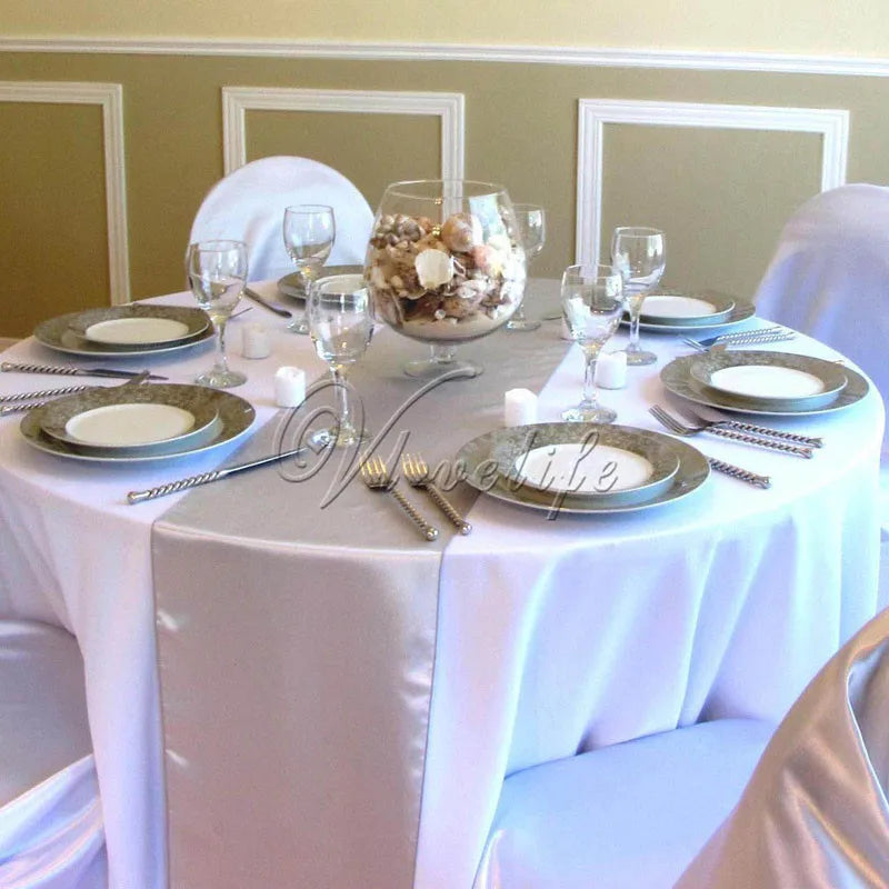 A formal dining table set with white linens, glassware, and a centerpiece of nuts and fruit.