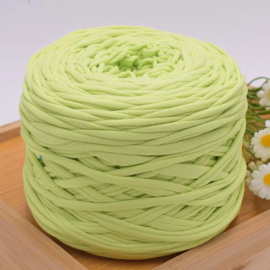 A ball of light green craft yarn for knitting and DIY displayed on a wooden surface.