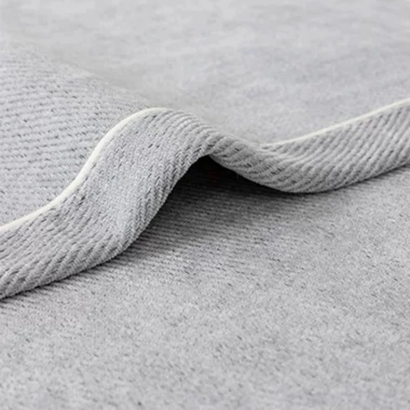 A close-up of a gray chenille sofa protector cover with a rolled edge.