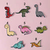 A set of eight iron-on patches featuring various dinosaur and animal figures in different colors