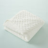A white, quilted baby name swaddle blanket folded neatly on a light blue surface.