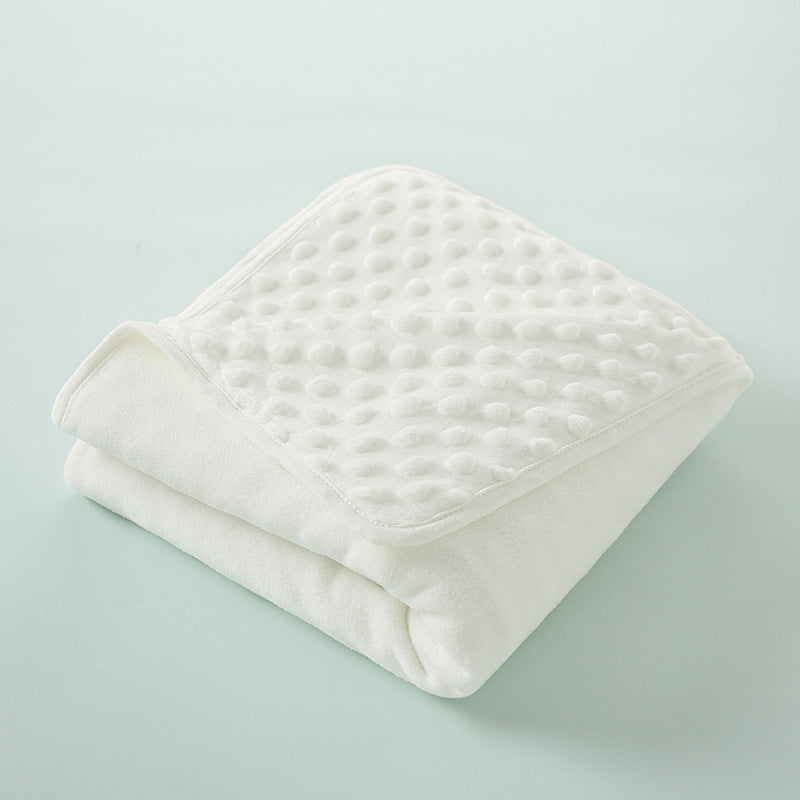 A white, quilted baby name swaddle blanket folded neatly on a light blue surface.