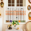 White lace cafe curtain with orange floral embroidery and butterfly applique hanging in a window.