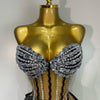 A gold-toned mannequin displays a sparkly diamond two-piece performance set with black accents.