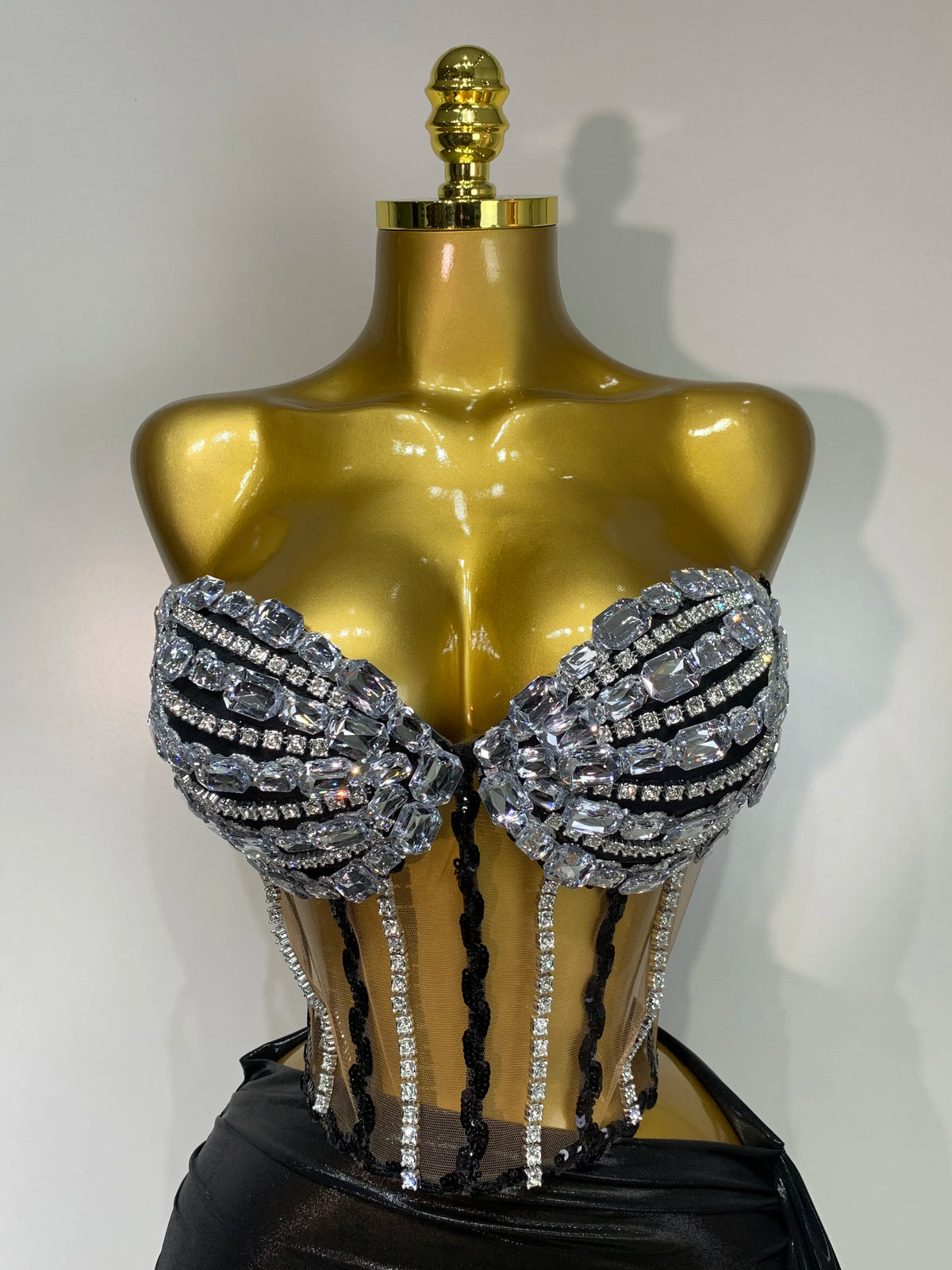 A gold-toned mannequin displays a sparkly diamond two-piece performance set with black accents.