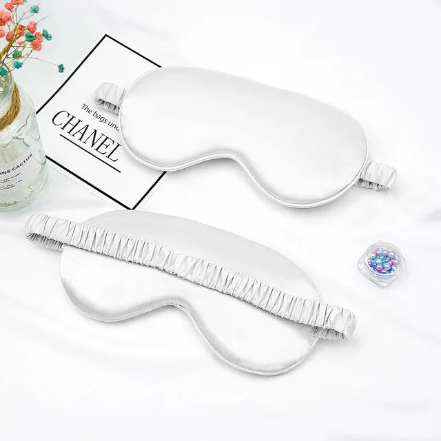 A white silk sleep mask is shown next to a glass jar and a piece of fabric, with text referencing Chanel.