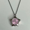 Silver chain necklace with a pink-faced star-shaped pocket watch charm.