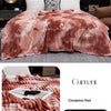 A fluffy cinnamon red tie-dye flannel fleece throw blanket draped over a sofa.