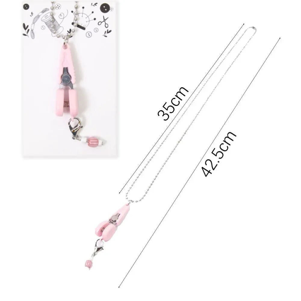 Pink mini precision sewing scissors with a protective cover displayed on a white background.