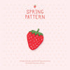 A pink patterned fabric featuring a red strawberry embroidery patch and text wishing beauty.