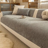 A beige striped slipcover on a sofa with light pillows and wooden paneling in a bright room.