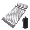 A mat and pillow set with a grid pattern of white circles on a dark gray background for acupressure relief.