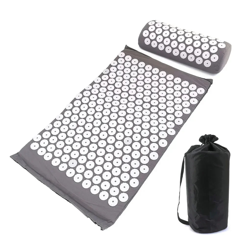 A mat and pillow set with a grid pattern of white circles on a dark gray background for acupressure relief.