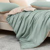 A light sage green luxury bamboo duvet cover set draped over a bed, featuring soft beige and mint green accents.