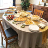 A long table set for a celebration featuring a gold sequin table runner and various appetizers.