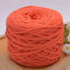 A ball of bright orange craft yarn for knitting and DIY displayed on a wooden surface.