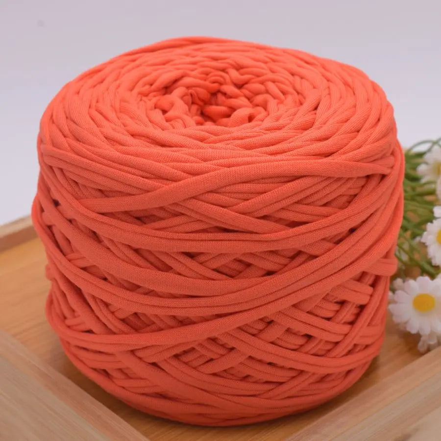 A ball of bright orange craft yarn for knitting and DIY displayed on a wooden surface.