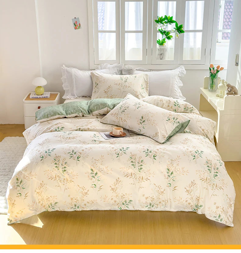 A white duvet cover set with a floral pattern featuring green and beige leaves displayed on a bed near a window.