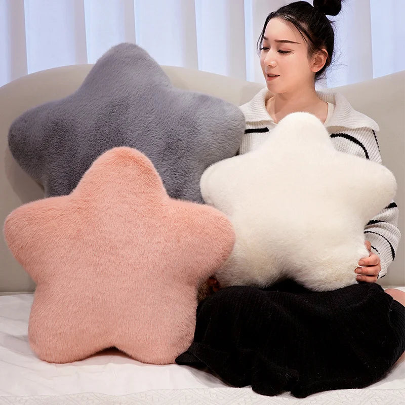 A woman is holding a white star-shaped decorative throw pillow and a gray star-shaped decorative throw pillow.