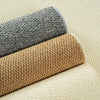 Two rolled sisal runner rugs, one gray and one tan, resting on a light beige background.