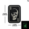 A black embroidered patch featuring a skull and spade design on a fabric backing.