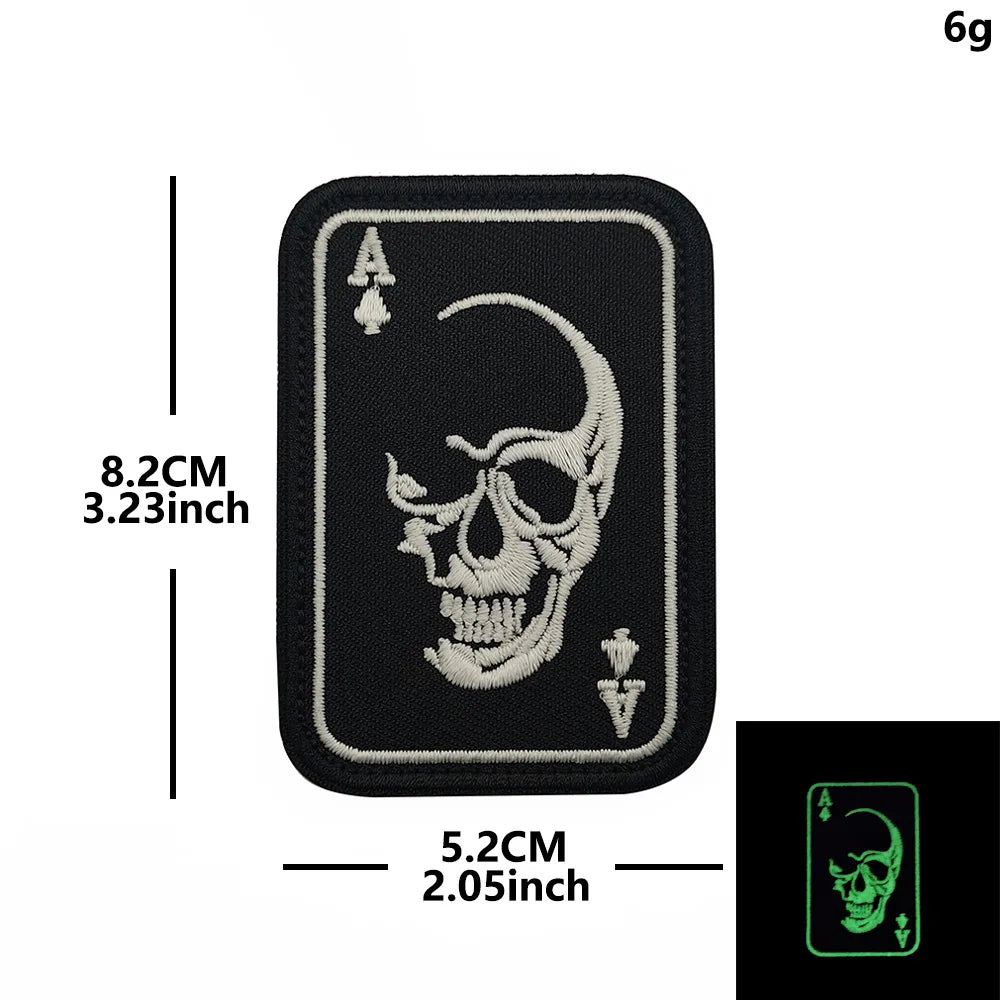 A black embroidered patch featuring a skull and spade design on a fabric backing.