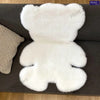 A white plush bear-shaped non-slip area rug resting on a dark gray surface.