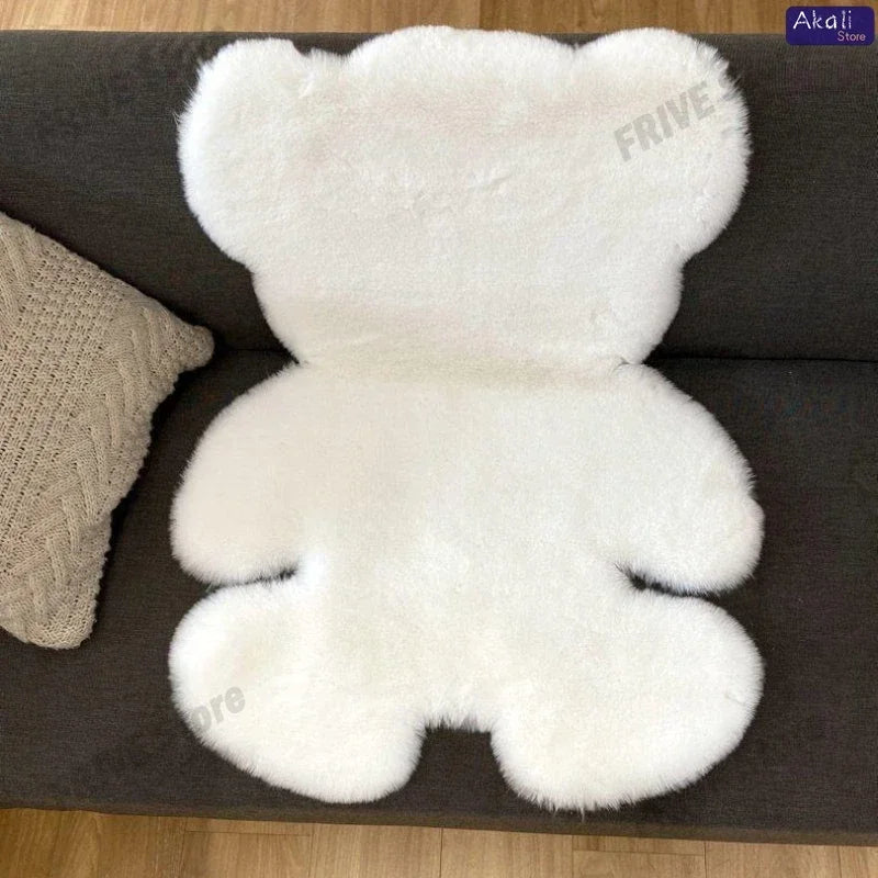 A white plush bear-shaped non-slip area rug resting on a dark gray surface.