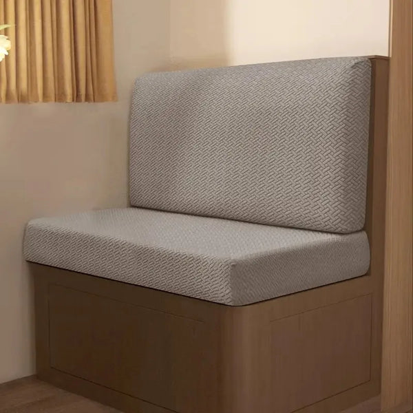 A beige stretch jacquard seat cover for a vehicle seat, shown on a wooden base.