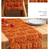 Orange felt table runner with pumpkin embroidery used as a festive Halloween decoration.
