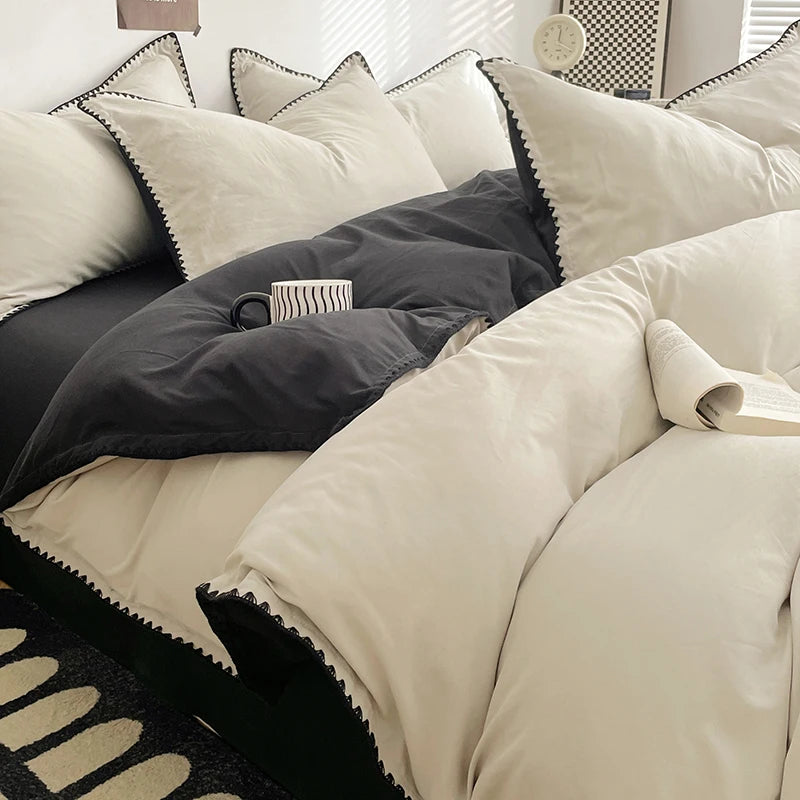 A close-up of a bed with a luxurious beige linen set featuring dark gray accents and striped pillows.