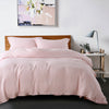 A pink luxury French linen duvet cover on a bed with a framed abstract painting above it.