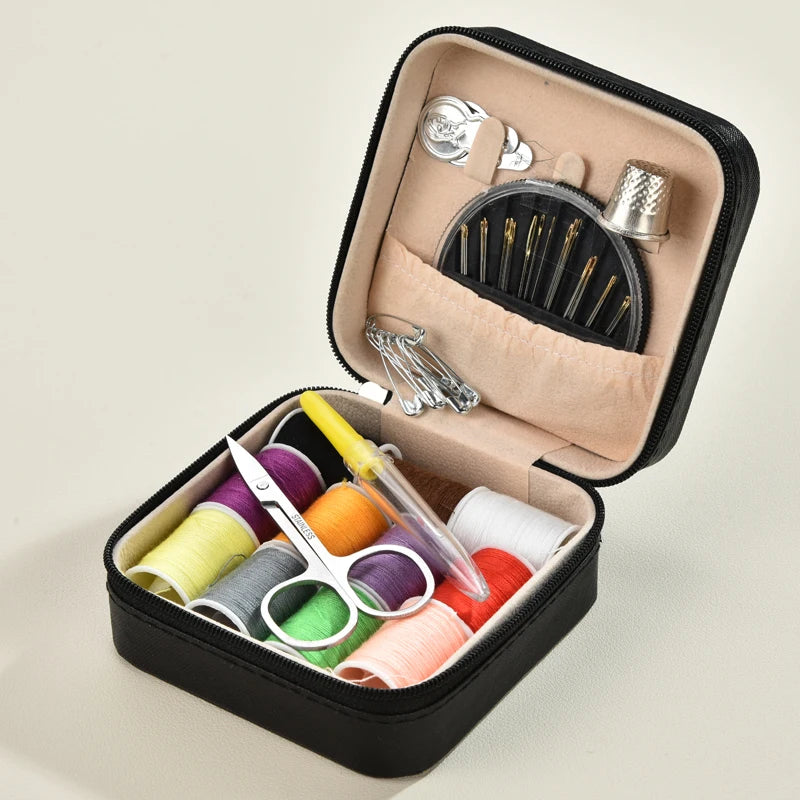 A black leather sewing box containing a complete hand sewing kit with needles and thread spools.