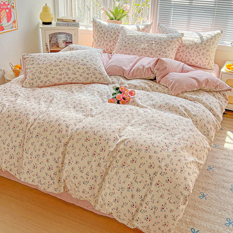 A pink and white floral printed bedding set with matching pillows on a bed.