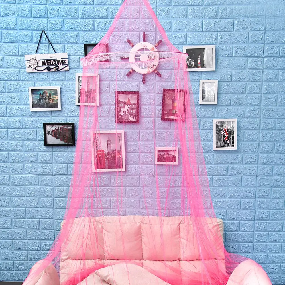 Pink lace dome mosquito net canopy draped over a light blue brick wall with framed pictures.