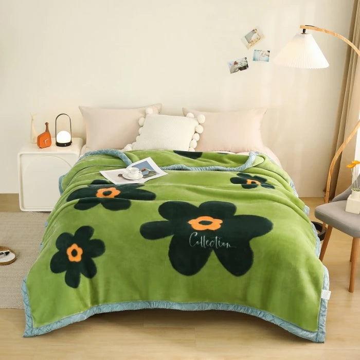 A plush green fleece blanket with a rose and peony floral pattern is displayed on a bed.