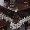 Lace embroidered PVC tablecloth with waterproof finish draped over a dark wood table.