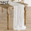 A white semi-sheer gauze table runner draped over a wooden dining table.